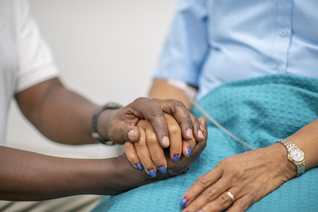 Elderly Patient is Comforted by Medical Personnel holding hands