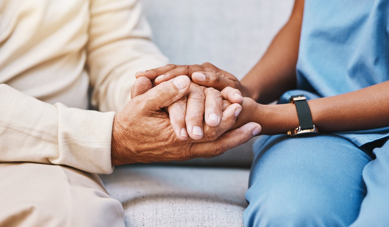 Nurse holding hands of elderly patient