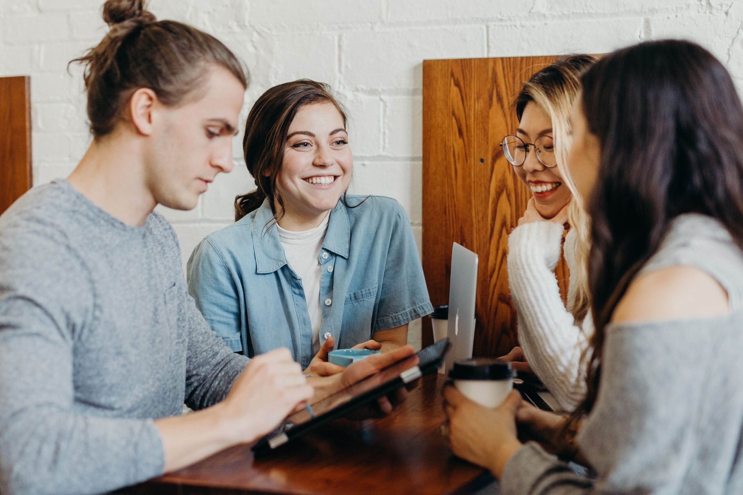 Group of young adults drinking coffee and using digital devices together