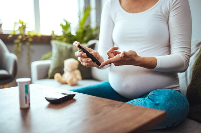 Pregnant woman sitting down and using an Epipen