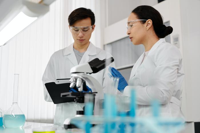 Clinical researchers in laboratory recording results on clipboard to demonstrate training and development