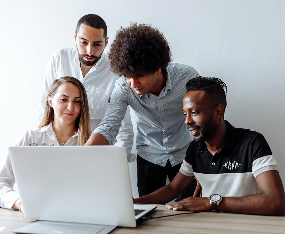 A diverse group of researchers looking at a laptop