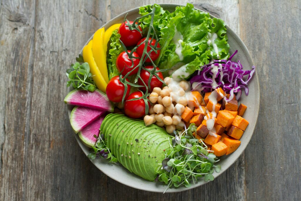 Plate with various vegetables and legumes, including salad, peppers, tomatoes, avocado, squash and chickpeas.