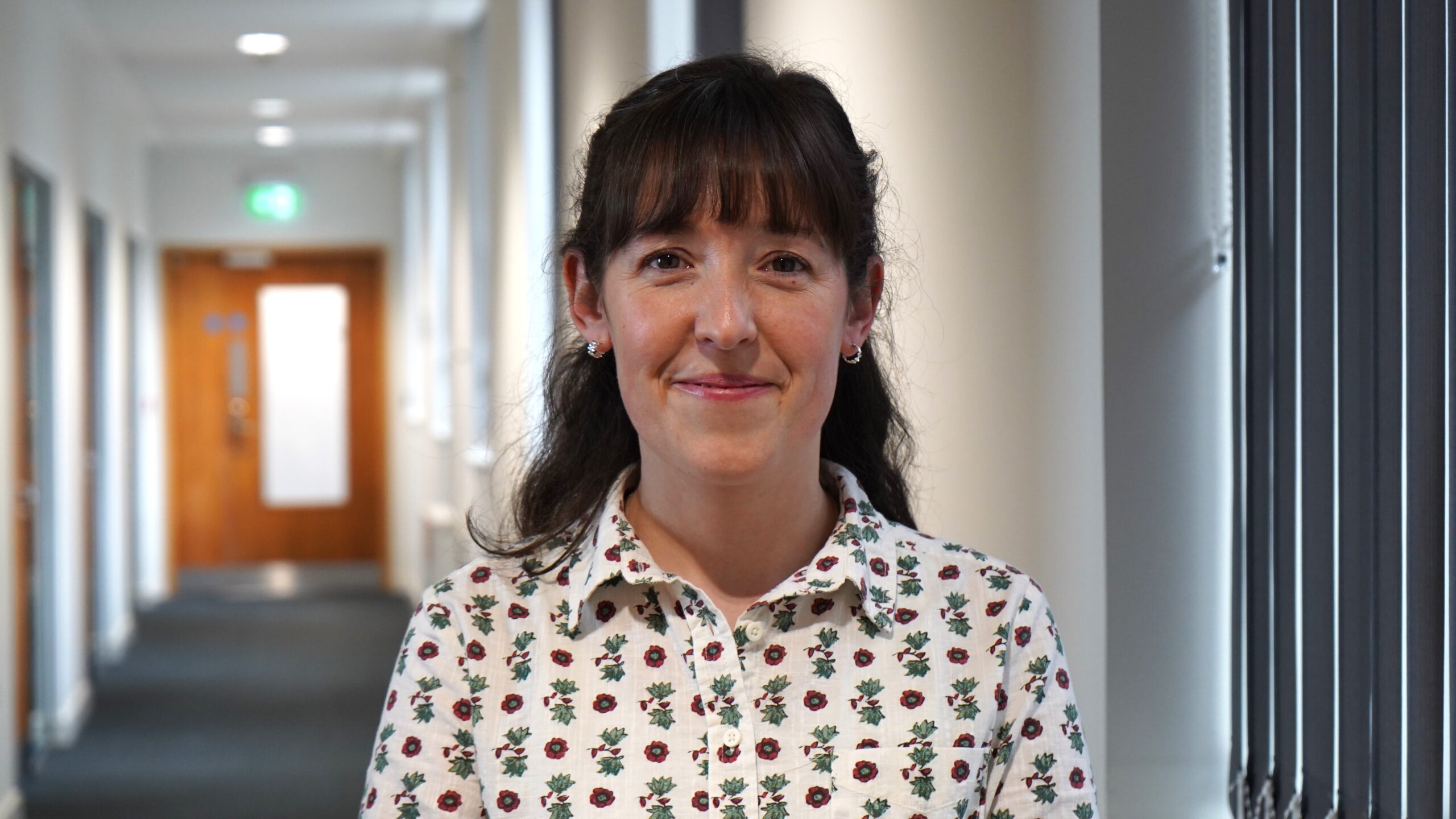 A woman standing in an office corridor