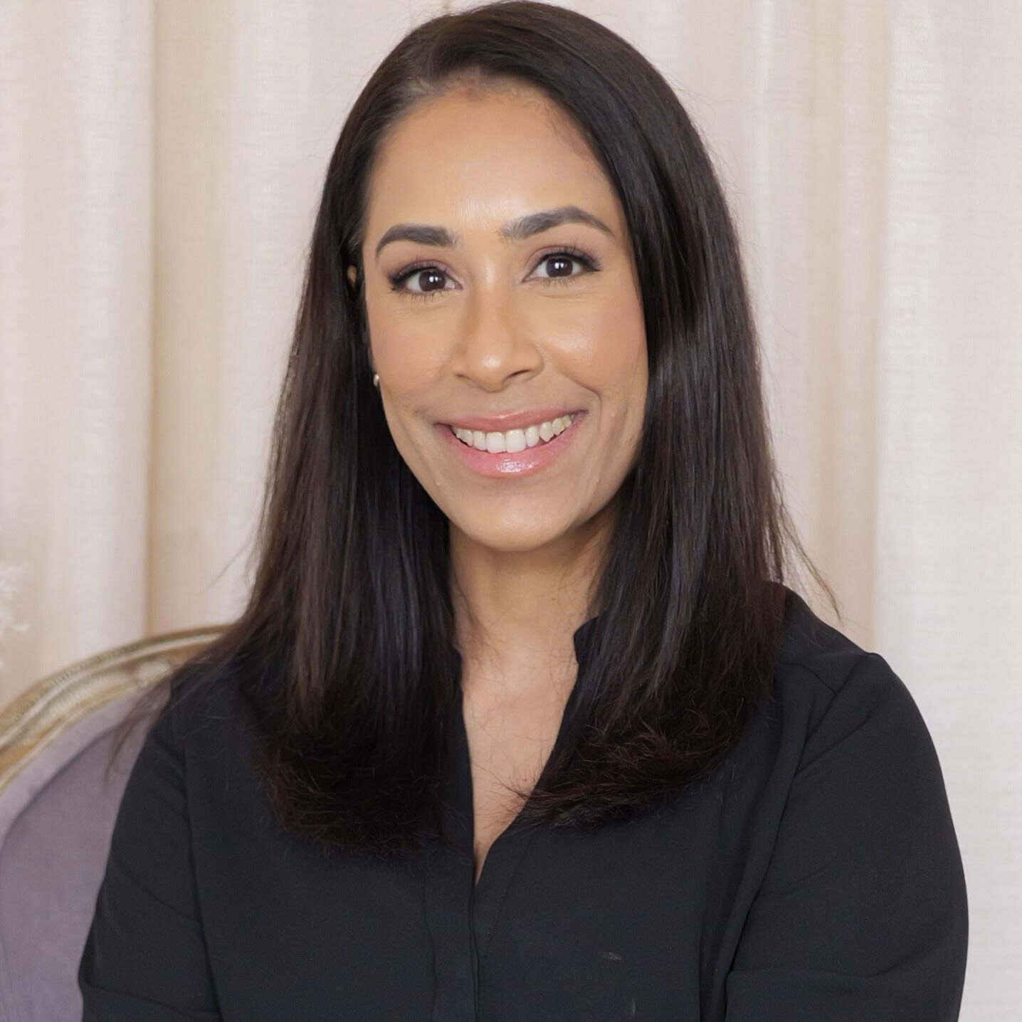 Harpreet Dibra smiling sitting on a chair in a professional picture