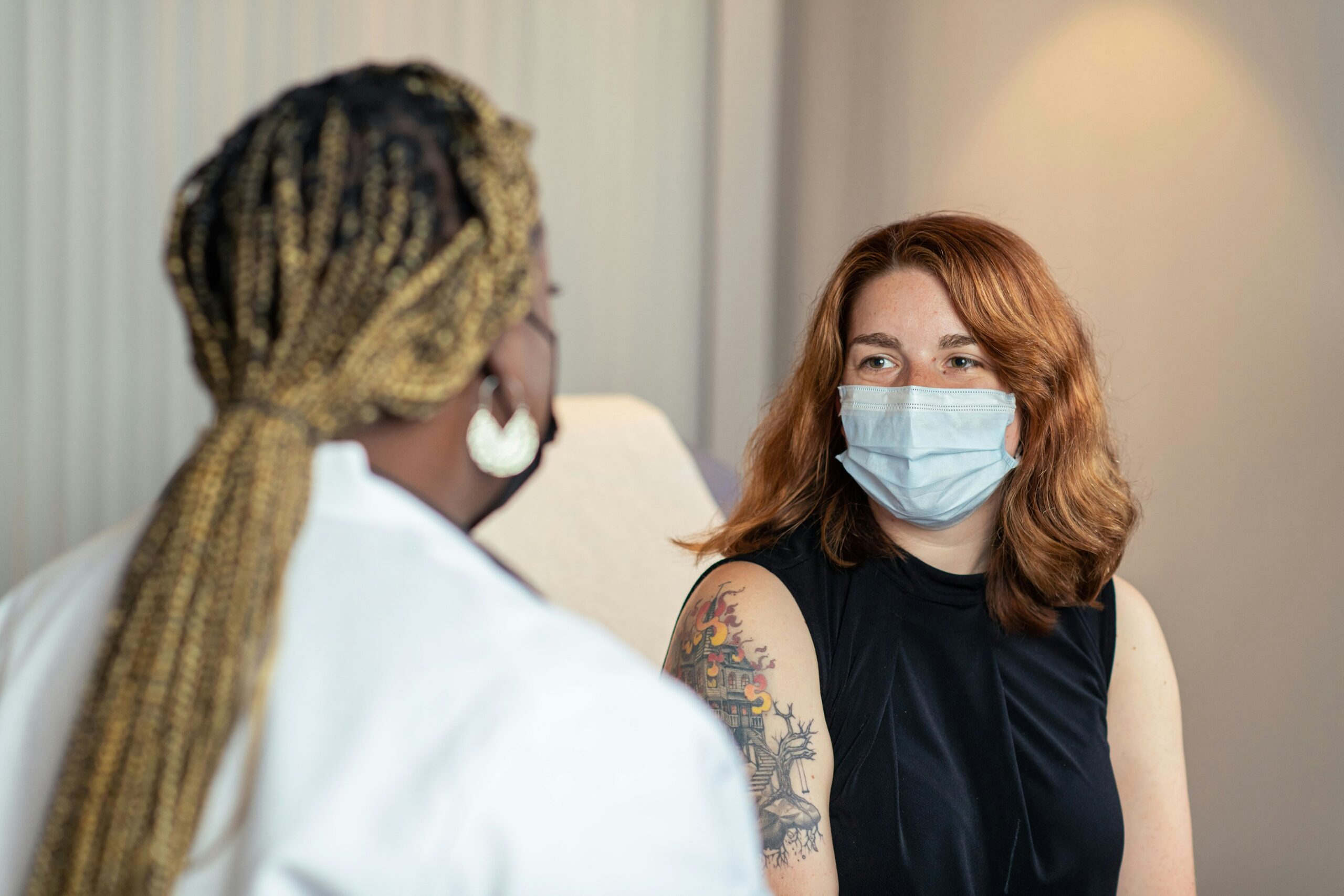 healthcare professional consulting with patient, while both wearing face masks