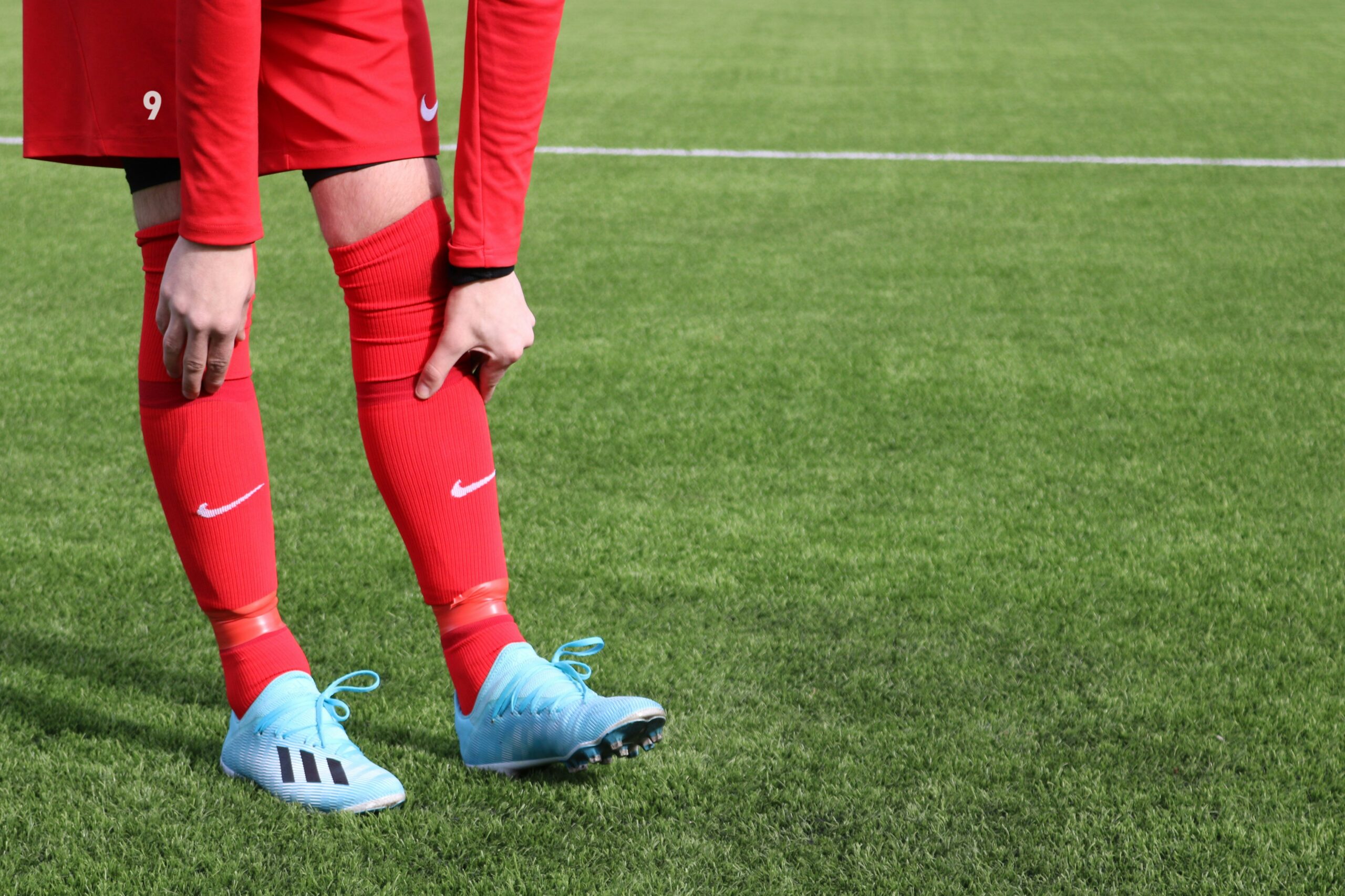 Man playing football touching painful knee