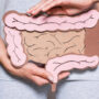Woman holding a cardboard model of intestines in front of body