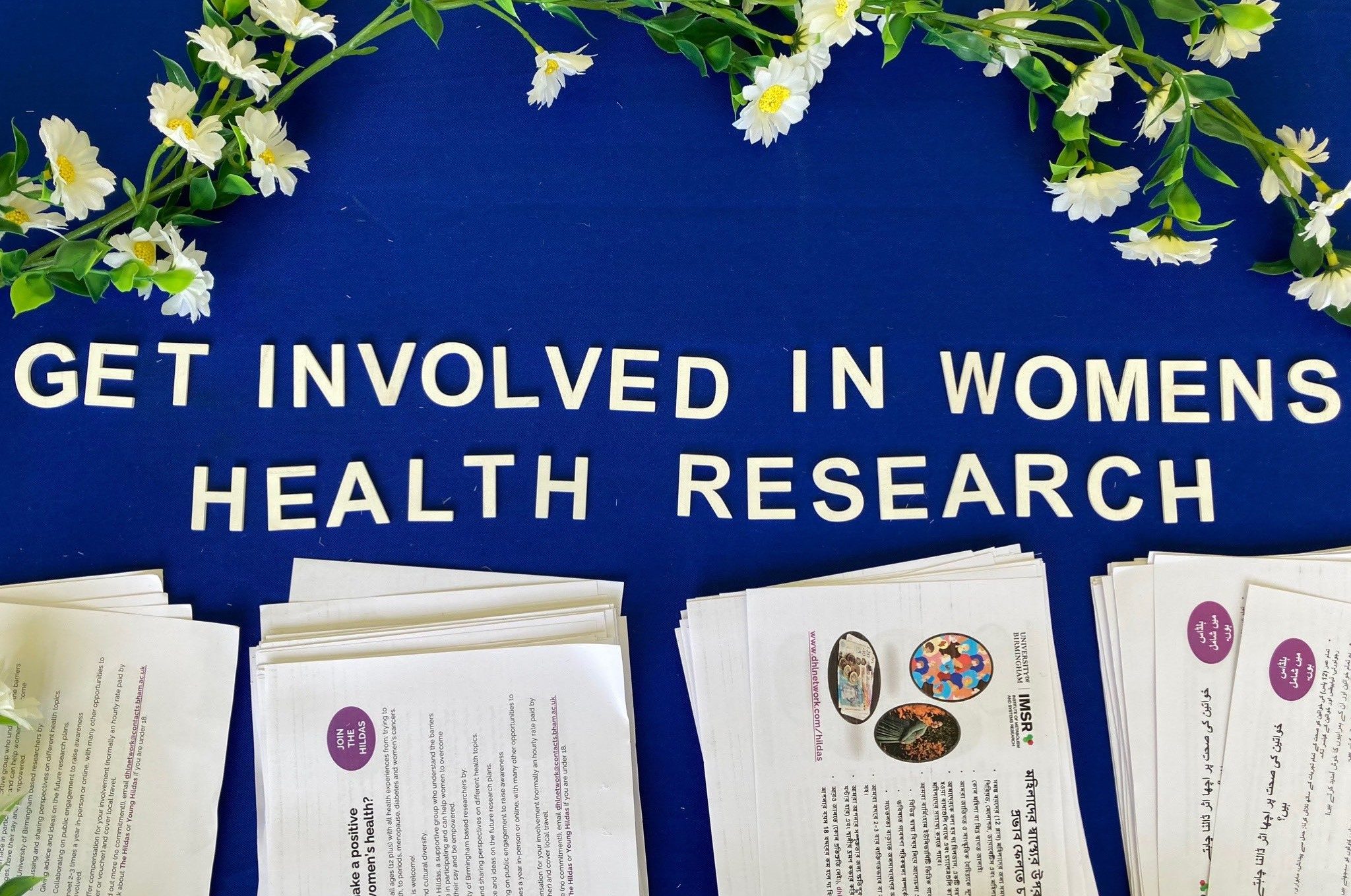 Lettering saying 'Get involved in women's health research' and information sheets on stand at Birmingham Mela festival