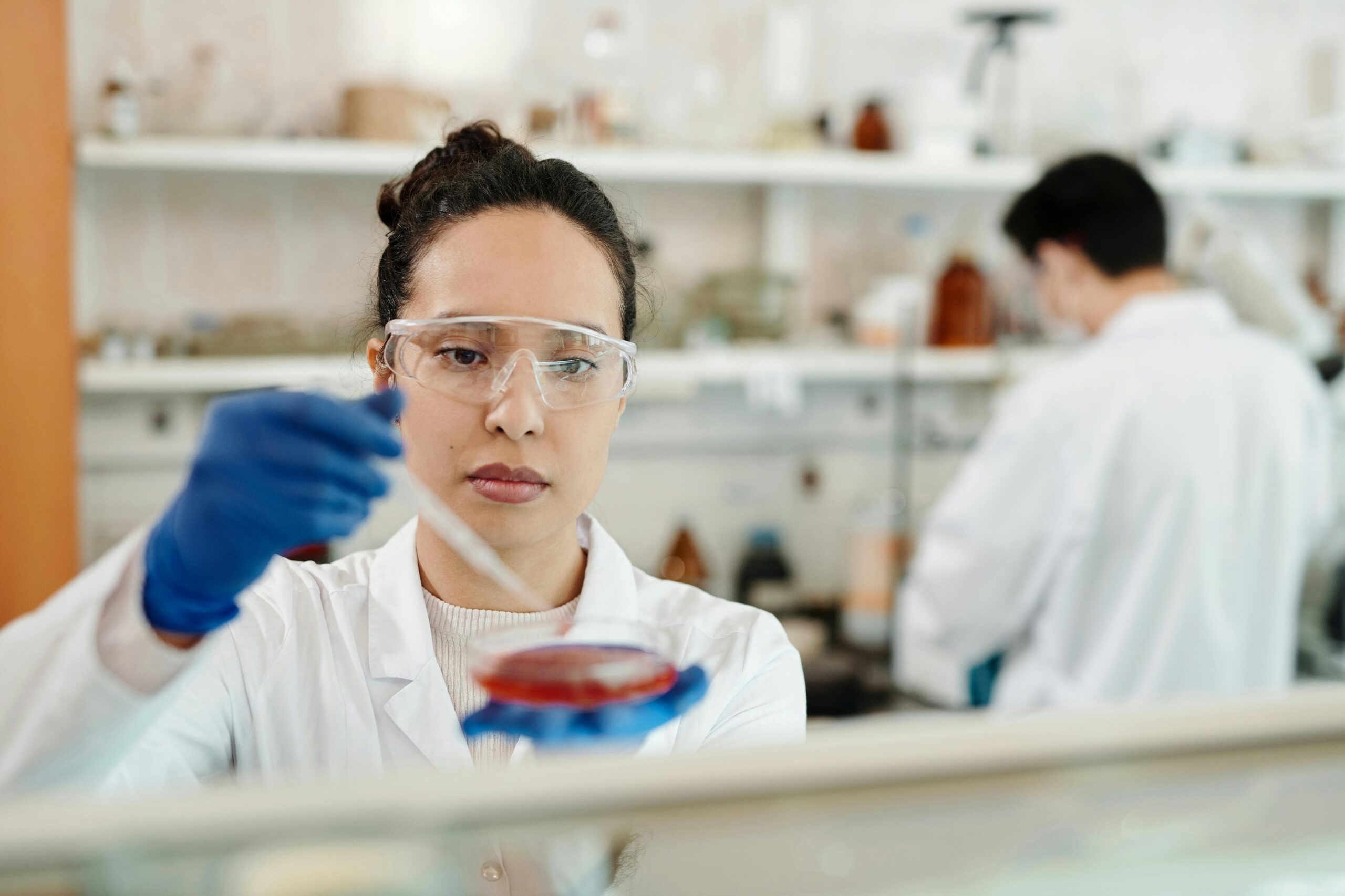 Researcher in a lab pipetting fluid from a petri dish