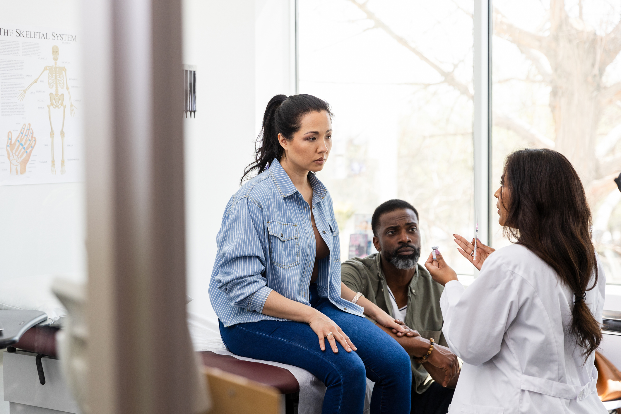 Fertility doctor consulting a couple, holding a syringe